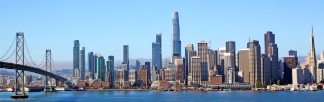 Photo of a San Francisco waterfront, with many skyscrapers and a bridge visible.